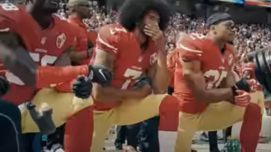 Colin Kaepernick arrodilla en el himno de Estados Unidos. Fuente: Canal de YouTube NFL Media Originals